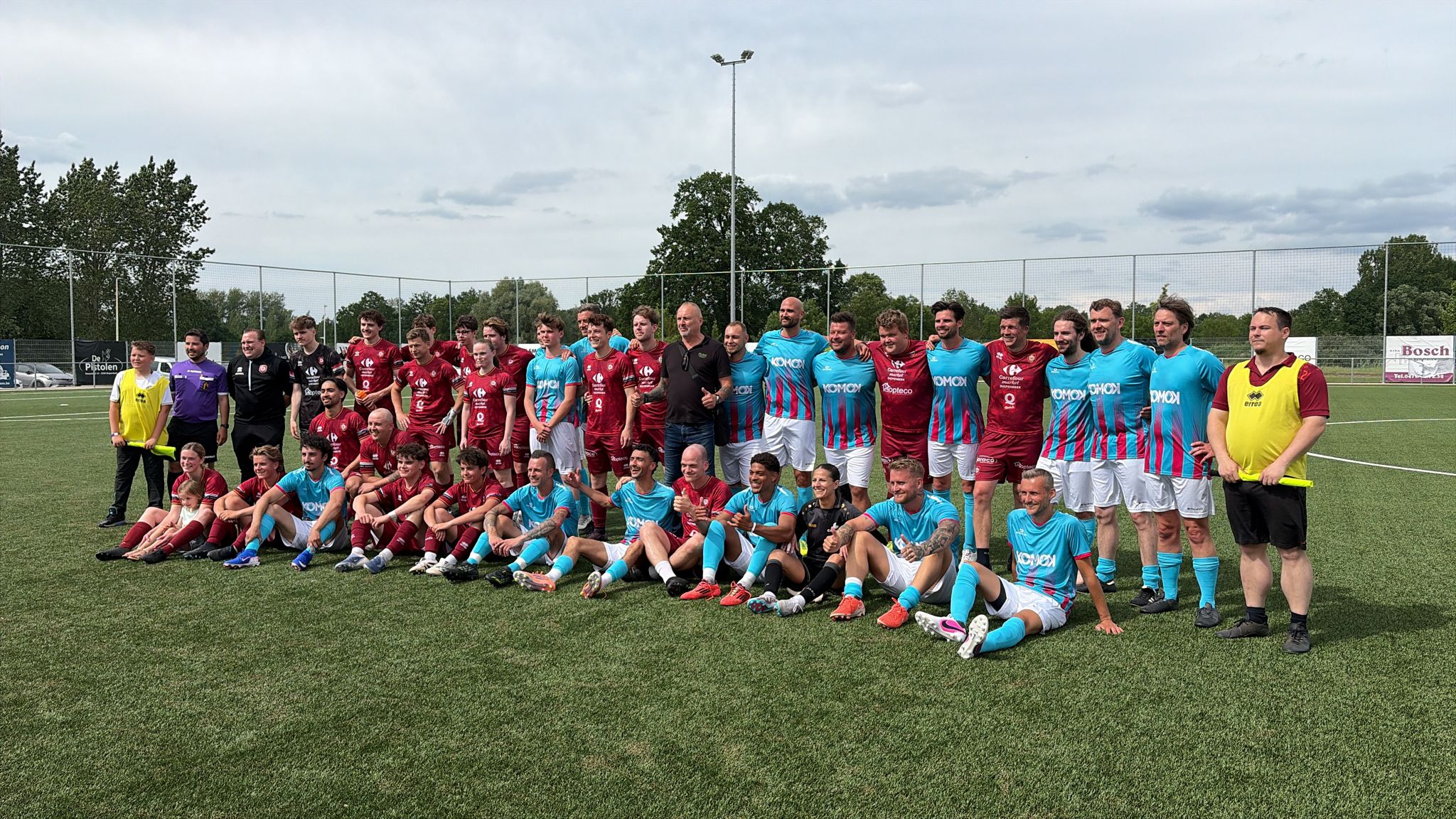 Voetbalwedstrijd KOMOK – teamfoto beide ploegen, juni 2026